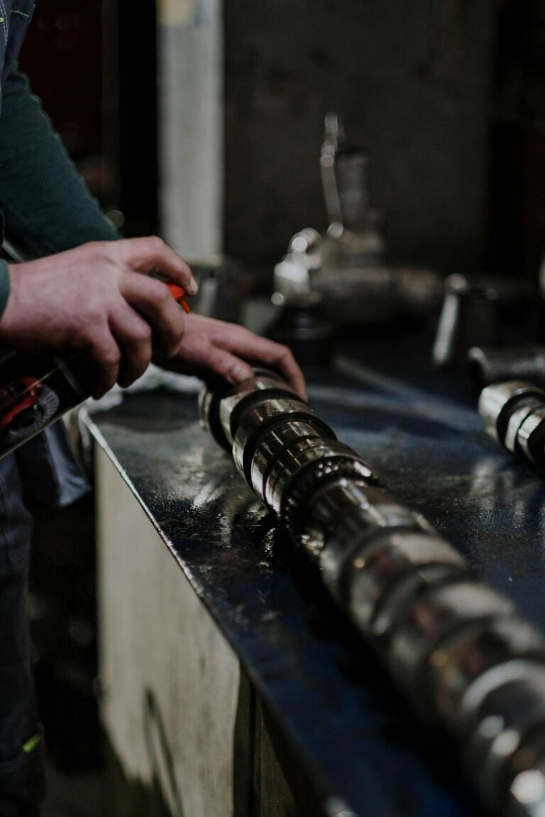 A Person Greasing a Part of a Metal Engine